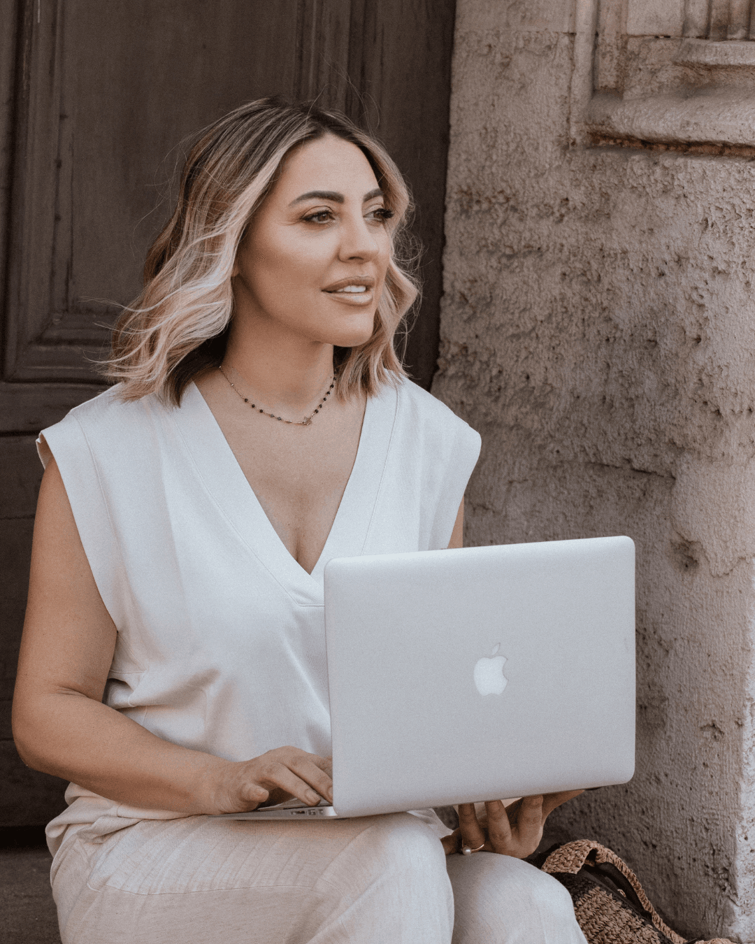 Ivana Andjić sedi sa laptopom u elegantnom ambijentu i simbolizuje pravu transformaciju kroz coaching program za žene