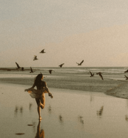 Žena hoda bosa po plaži u zoru – simbol emocionalnog oslobađanja posle raskida bez objašnjenja.